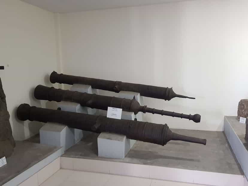 Three large cast-iron cannon of the Ahom period displayed on plinths in a museum