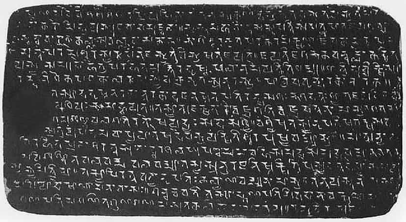 A dark rectangular copperplate covered edge to edge in rows of engraved early eastern-Brahmi letters, the surface worn at the left edge