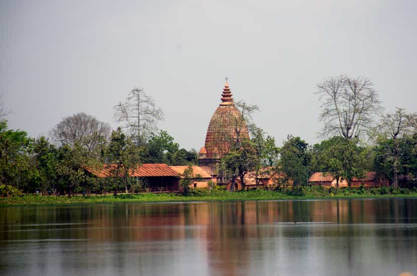 The Joysagar tank seen across the water to a bankside Ahom dol temple and a low pillared hall, reflected in the great sheet of water