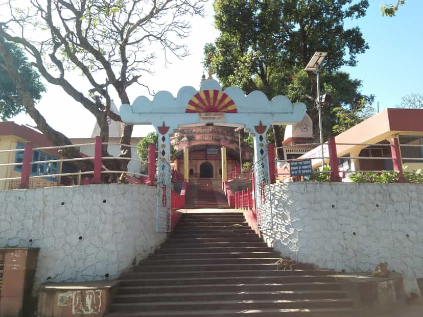 An ornamented archway painted with a red-and-orange sunburst over the flight of steps climbing to the Navagraha temple