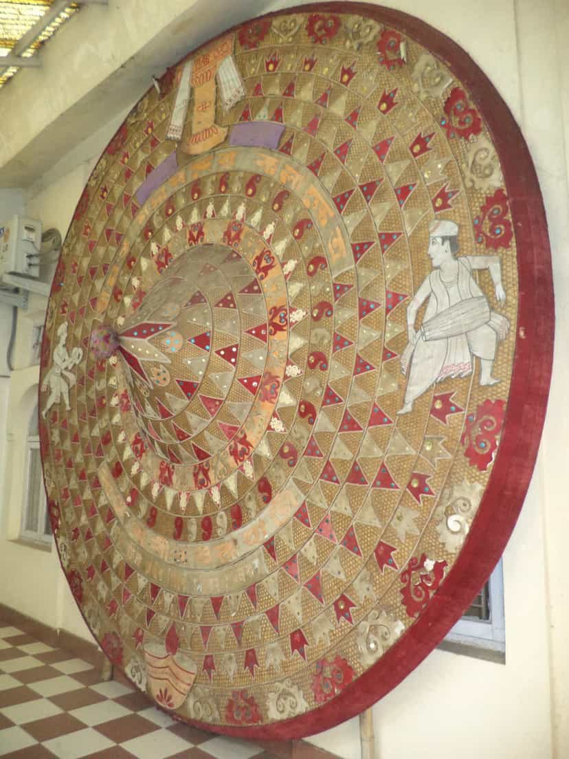 A very large phulam japi faced in red and gold cloth, worked all over with triangular appliqué, mirrors and figural motifs
