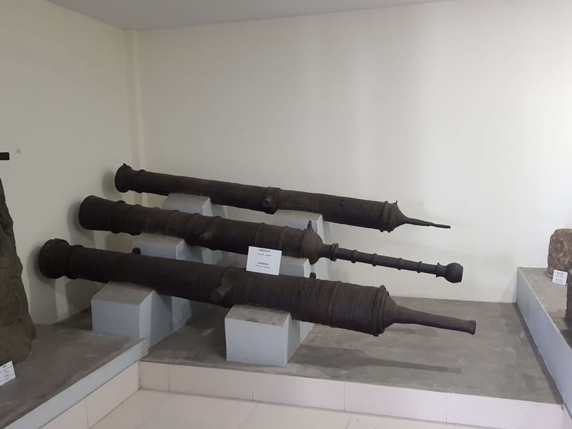 Three large cast-iron cannon of the Ahom period displayed on plinths in a museum