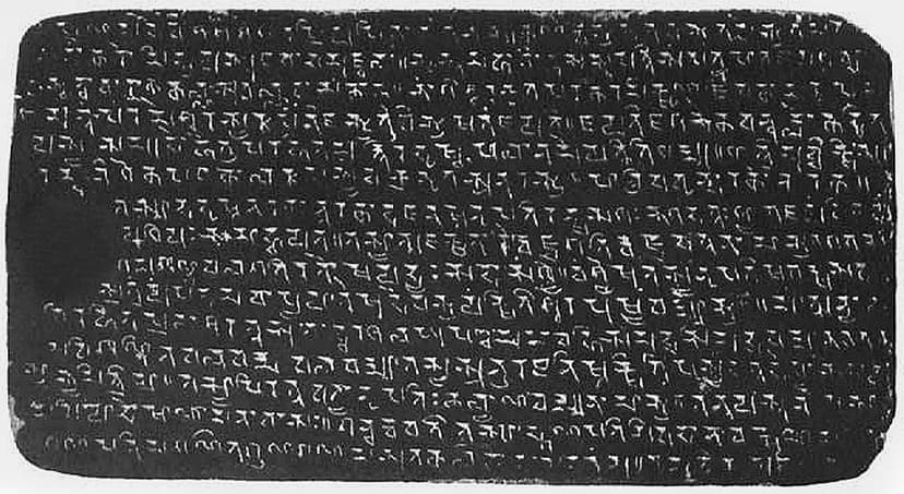A dark rectangular copperplate covered edge to edge in rows of engraved early eastern-Brahmi letters, the surface worn at the left edge