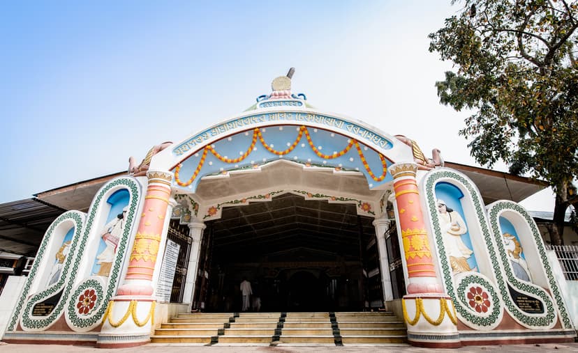White and pink ornamented entrance porch of the Dhekiakhowa prayer-hall, hung with marigold garlands, with steps leading up to the dark interior