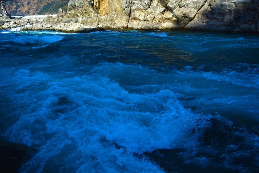 Turbulent blue waters of the Lohit rushing past a rock face at Parshuram Kund