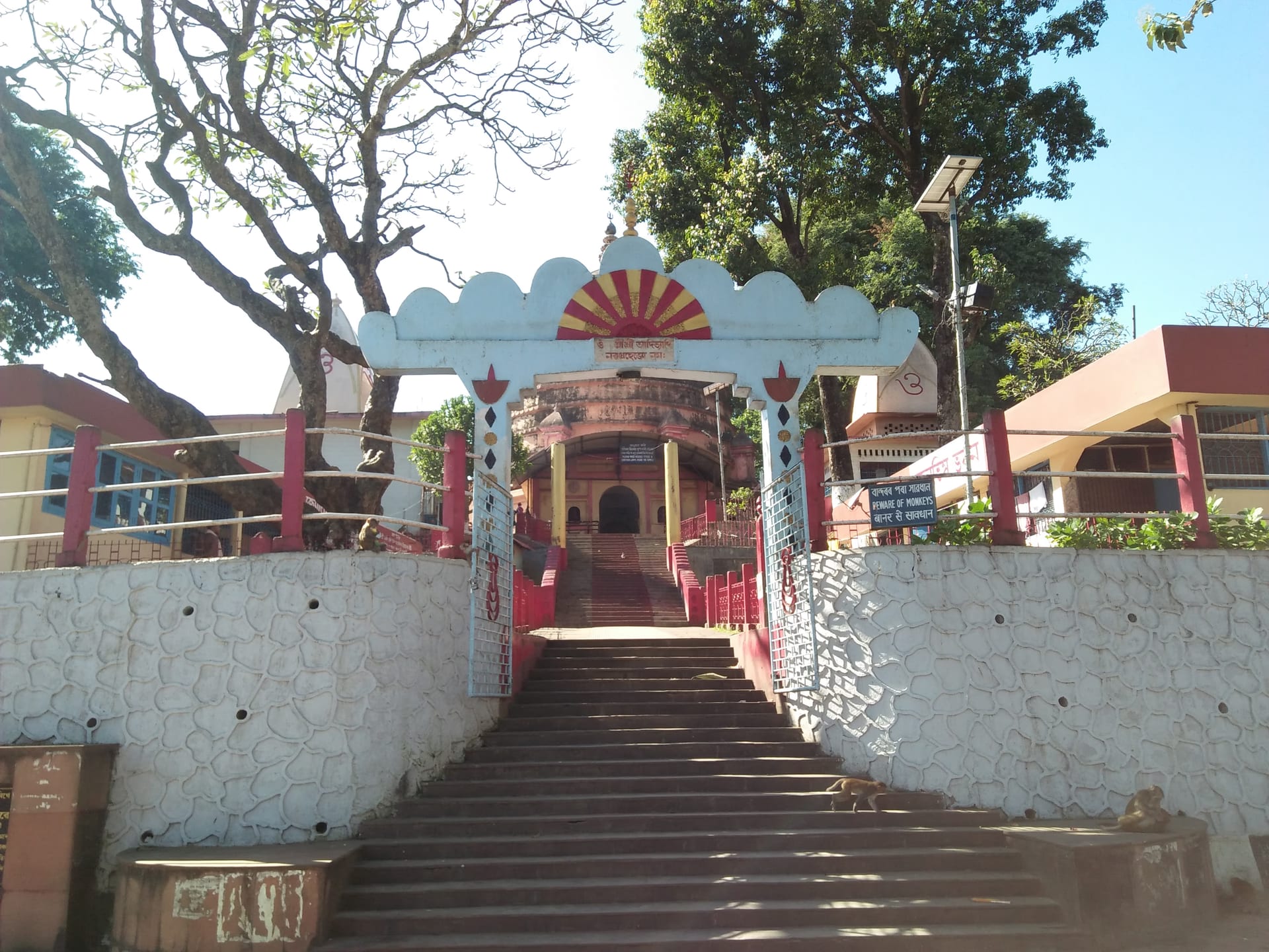 An ornamented archway painted with a red-and-orange sunburst over the flight of steps climbing to the Navagraha temple