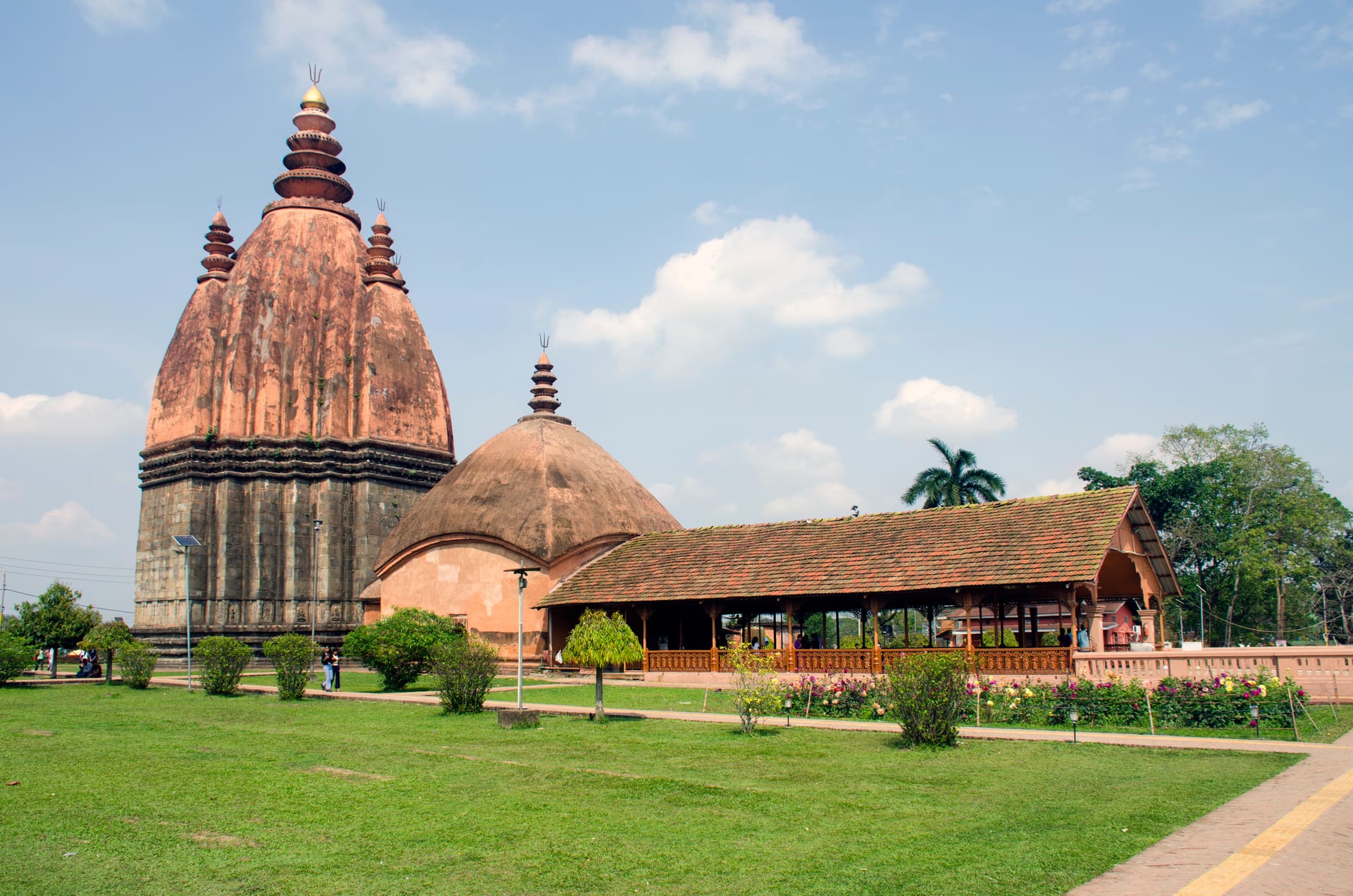 The tall curvilinear brick spire of the Sivadol rising above its mandapa hall at Sivasagar