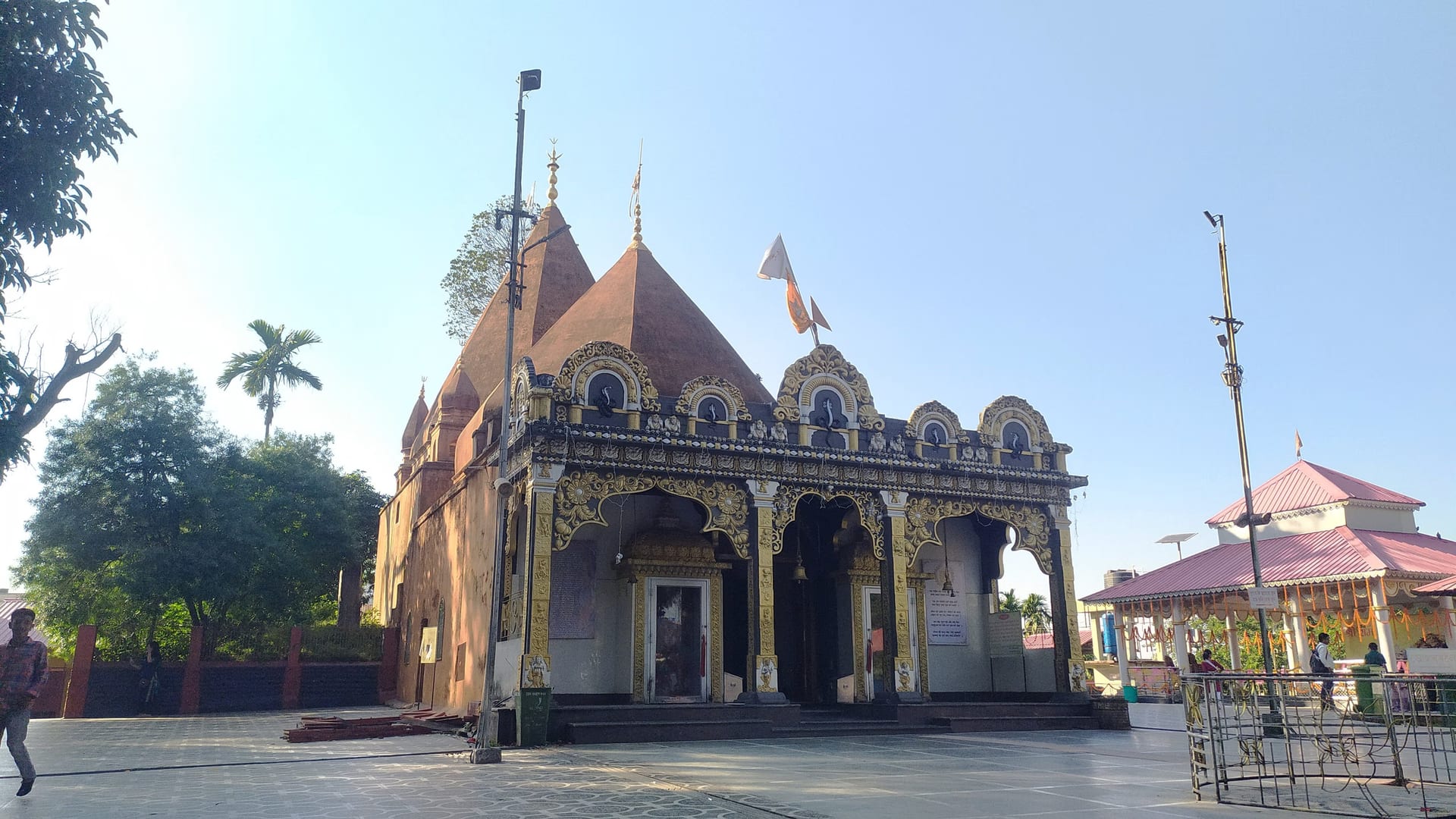 White-spired Siva temple with a gilded ornamented porch and a paved courtyard