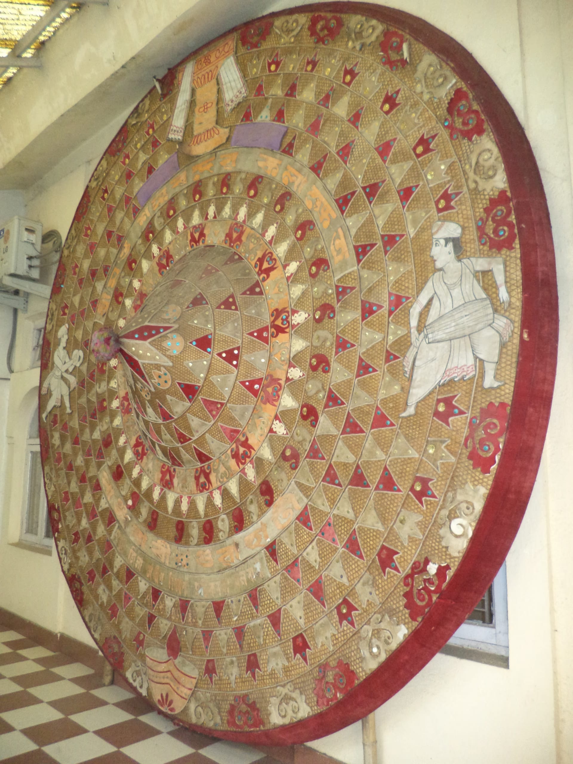 A very large phulam japi faced in red and gold cloth, worked all over with triangular appliqué, mirrors and figural motifs