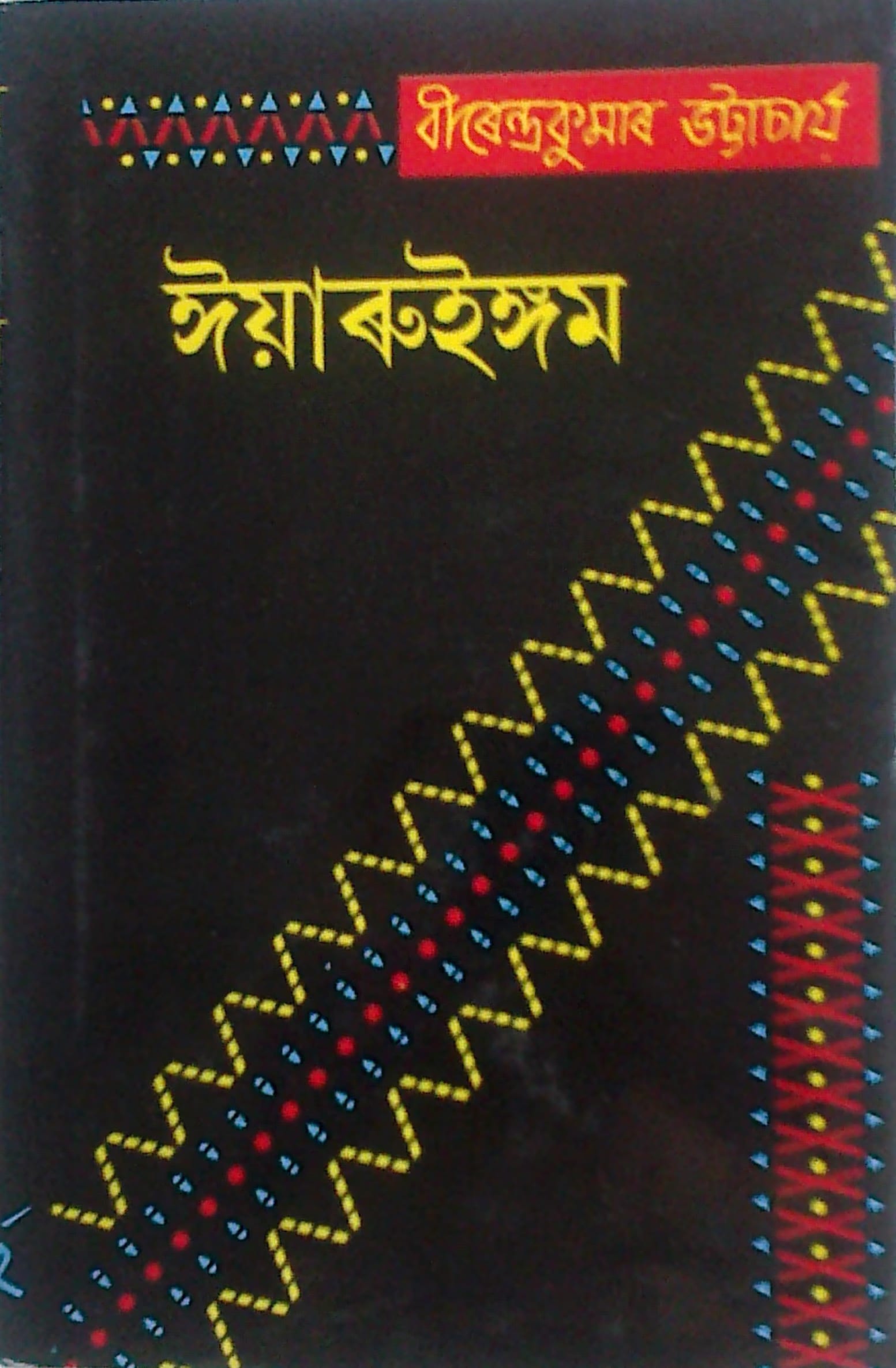 Black book cover printed with the Assamese title Iyaruingam and the author's name, with a woven tribal-textile motif running diagonally