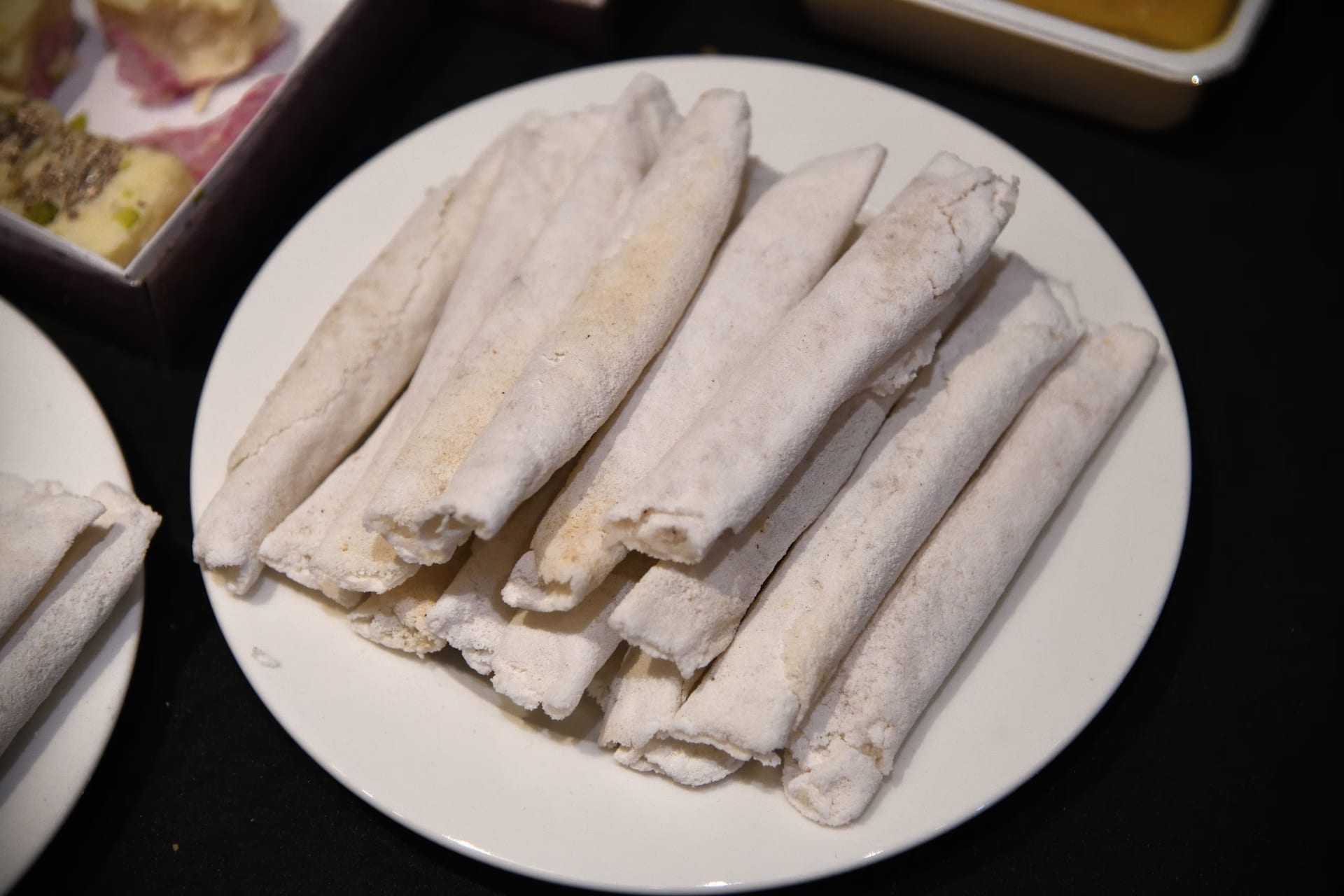 A plate of pale rice-flour cones, each rolled around a coconut and jaggery filling