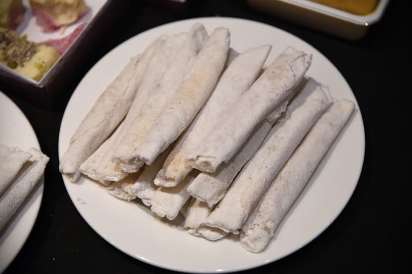 A plate of pale rice-flour cones, each rolled around a coconut and jaggery filling