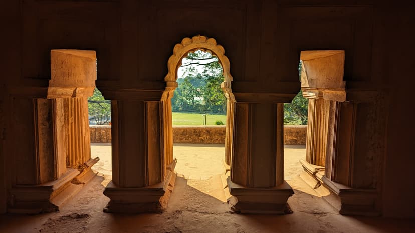 Cusped masonry archway inside the Kareng Ghar palace at Garhgaon, opening onto green grounds
