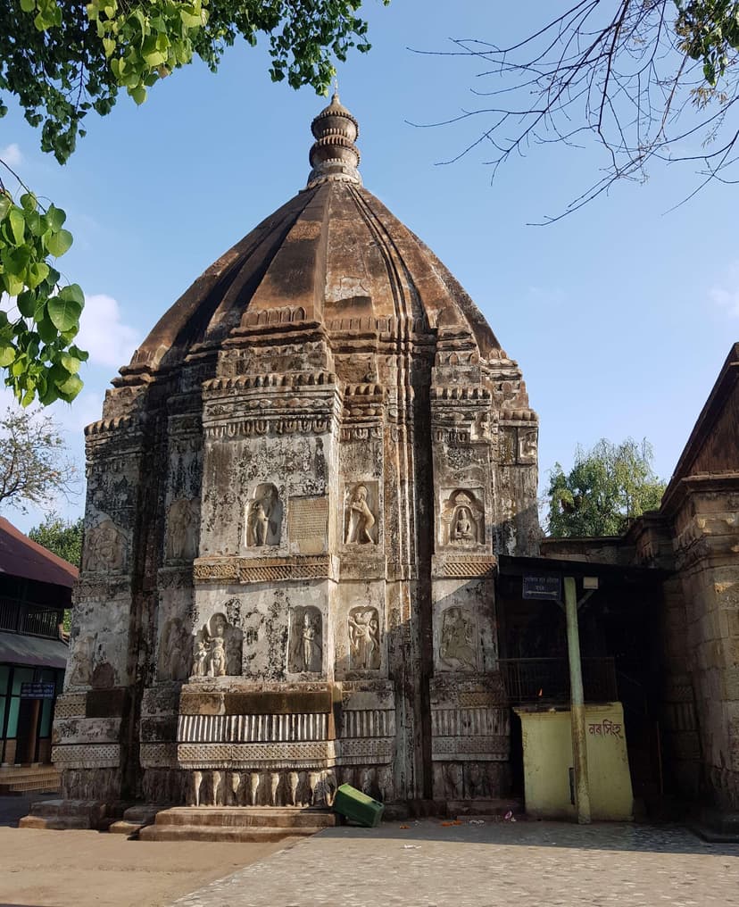 Stone curvilinear shikhara of the Hayagriva Madhava temple with stacked figural niches above a carved elephant base course