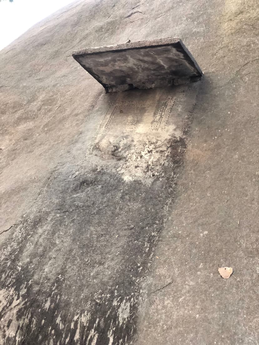 A large domed granite boulder with a small dark marker plaque fixed above a bordered incised inscription panel