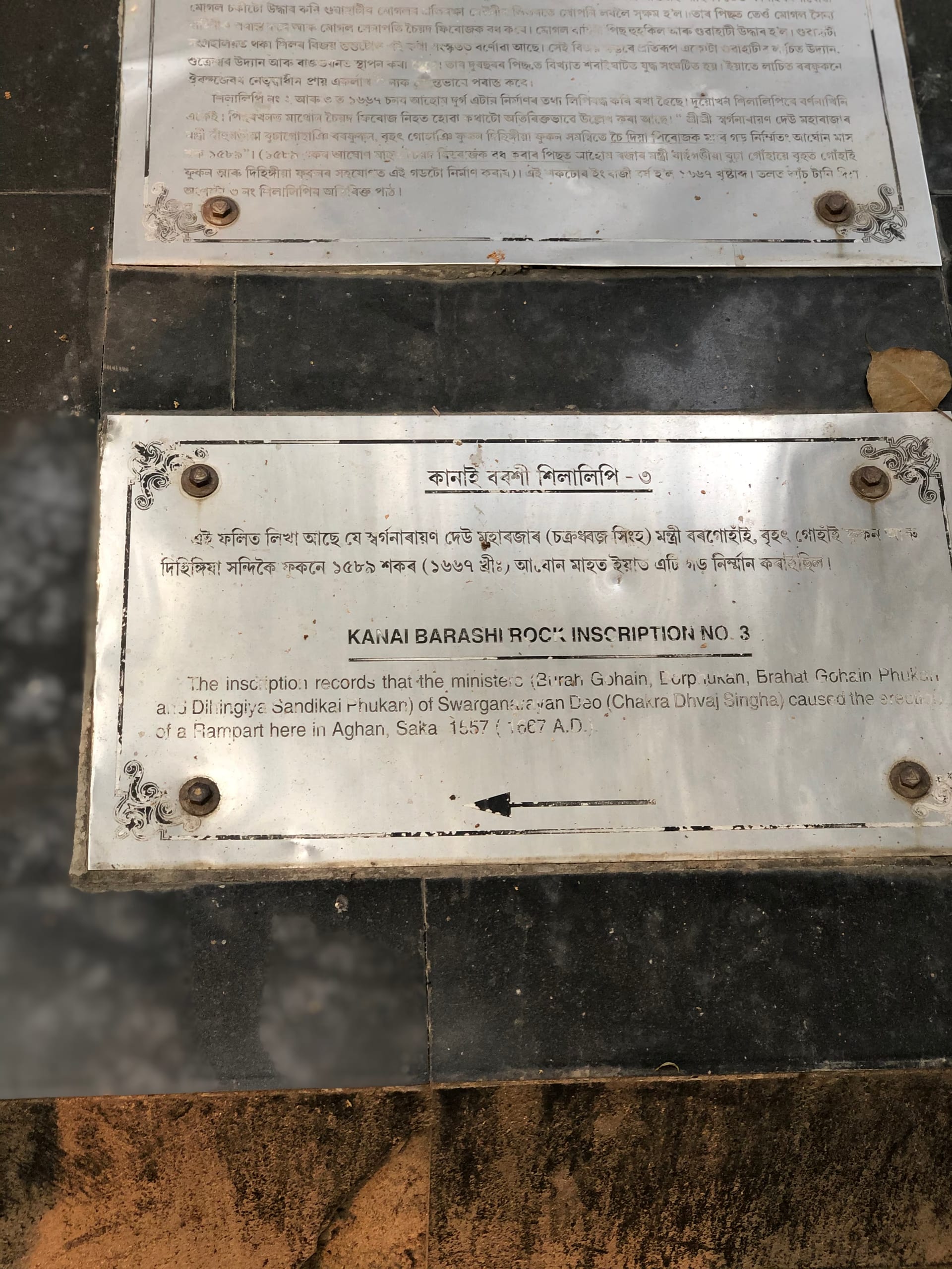 A bilingual metal site plaque reading Kanai Barashi Rock Inscription No. 3, recording an Ahom rampart of Saka 1589 / 1667 CE