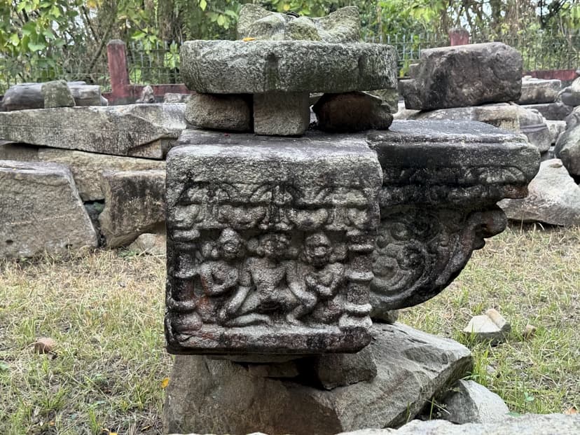 A ribbed circular amalaka stone set on a carved block with a frieze of small figures and a scrolled makara bracket