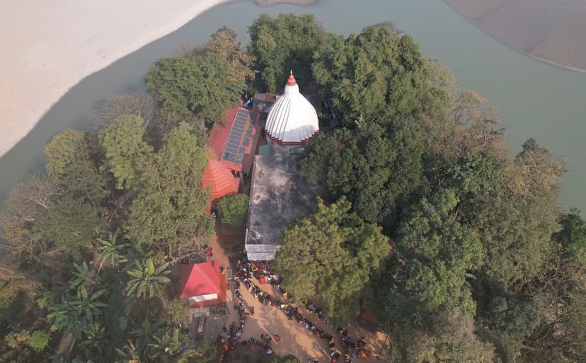 Aerial view of the white ribbed dome of the Umananda temple rising from a small forested island, the Brahmaputra and its sandbars around it