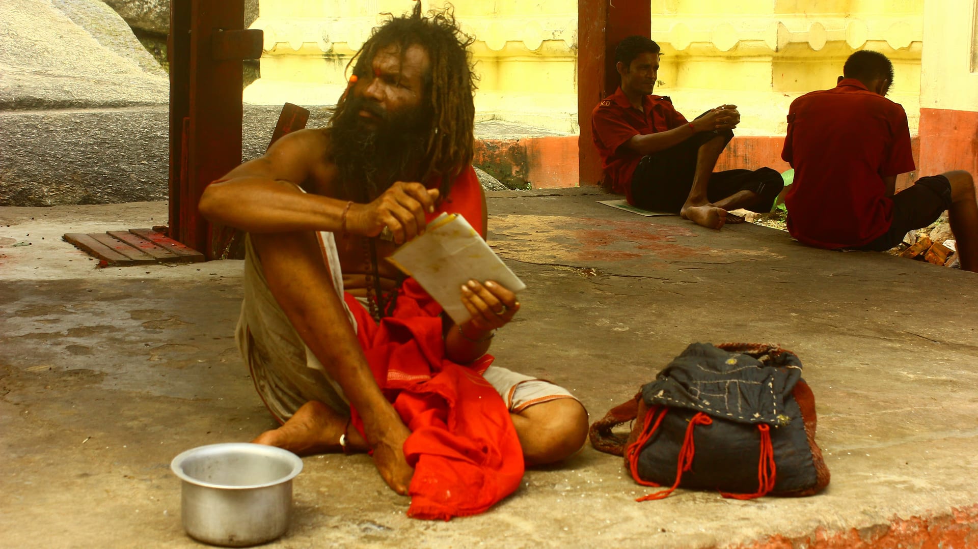 A tantric sadhu with long matted hair seated reading a manuscript on the grounds of the Kamakhya Temple