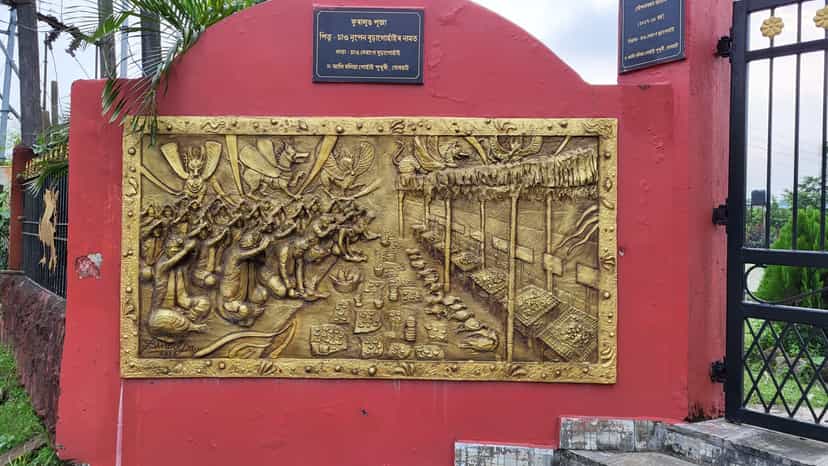 Golden relief plaque on a red gateway showing a row of Tai-Ahom priests and ritual figures performing an offering, with vessels laid out before them